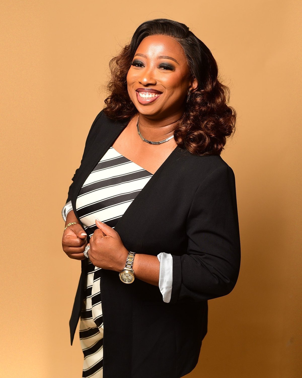 Kemi laughing, holding the lapels of her blazer