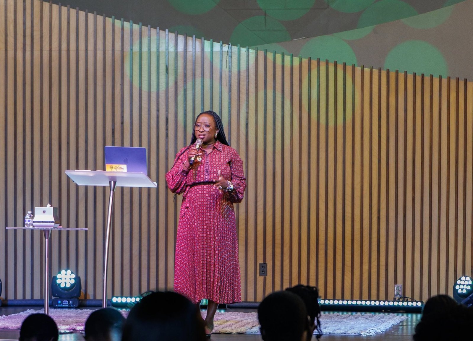 Kemi speaking on stage to a seated audience